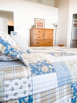 Una camera da letto con un letto, una cassettiera in legno, un quadro incorniciato e una lampada.
