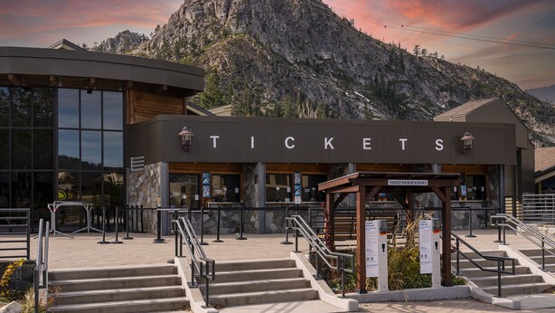 A ticket booth with a mountain backdrop, featuring a modern design with large windows and a stone facade.