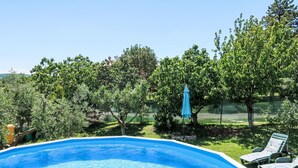 A swimming pool with a blue interior, surrounded by lush greenery and trees. - Vacation home Laura by Interhome (Pićan)
