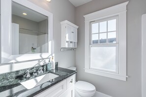 A bathroom with a large mirror, a sink with a granite countertop, a toilet, and a window with frosted glass. - Bourbon n Horses themed 3B/2Ba home in beautiful Chevy Chase neighborhood! (Lexington)