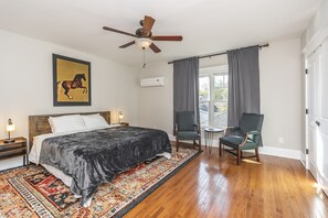 A bedroom with a large bed, a ceiling fan, a rug, two chairs, and a window with curtains. - Bourbon n Horses themed 3B/2Ba home in beautiful Chevy Chase neighborhood! (Lexington)