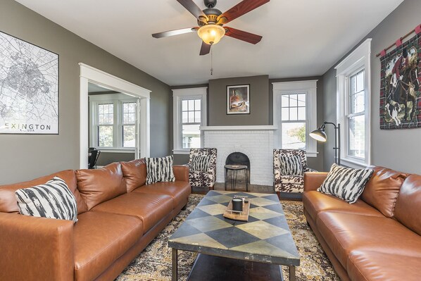 A living room with two brown leather sofas, a patterned coffee table, a fireplace, and a ceiling fan. - Bourbon n Horses themed 3B/2Ba home in beautiful Chevy Chase neighborhood! (Lexington)