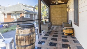 A covered outdoor patio with wicker furniture, two wooden barrels, and a ceiling fan. - Bourbon n Horses themed 3B/2Ba home in beautiful Chevy Chase neighborhood! (Lexington)