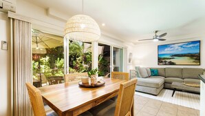 Un comedor con una mesa y sillas de madera, una lámpara colgante y vistas al exterior.