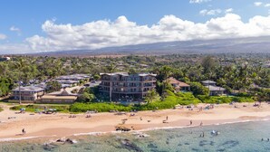 Ein Strandhotel mit mehreren Gebäuden, einem Sandstrand und blauem Himmel.