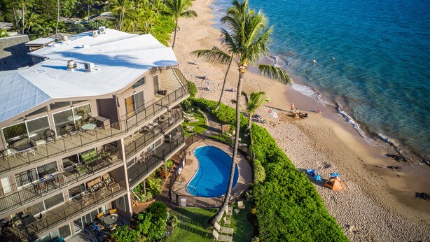 A multi-story hotel with a rooftop pool, beach access, and a view of the ocean.
