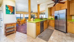 A modern kitchen with wooden cabinets, a stainless steel refrigerator, and a green countertop.