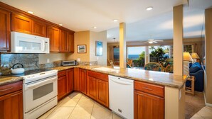 A kitchen with wooden cabinets, a microwave, stove, and dishwasher. - Hale Hui Kai 213 Oceanfront!! (Kihei)