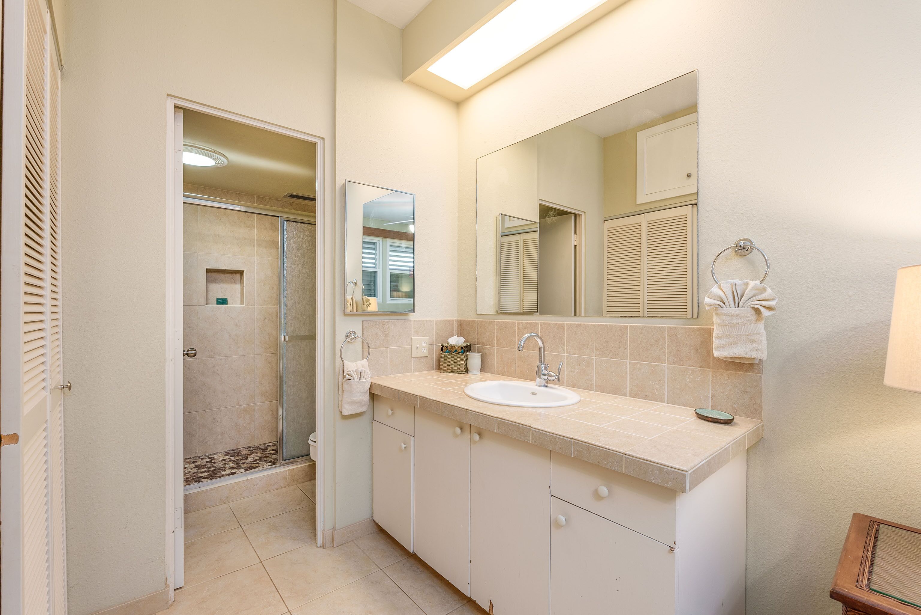 A bathroom with a sink, mirror, and shower.