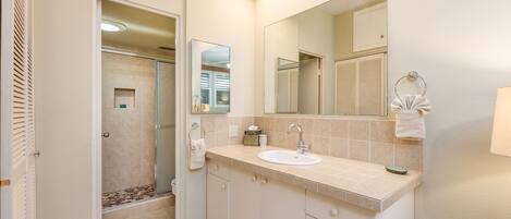 A bathroom with a sink, mirror, and shower.