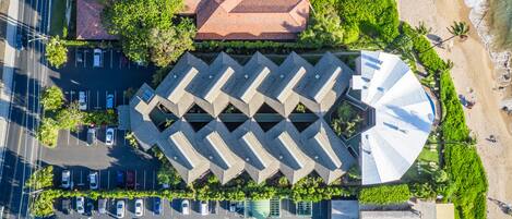 An aerial view of a hotel with a parking lot, a swimming pool, and a beach.