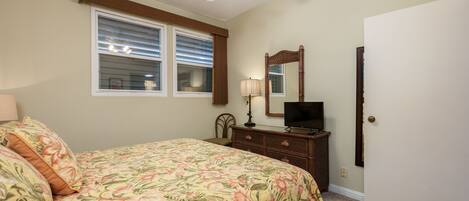 A bedroom with a bed, dresser, mirror, and ceiling fan.