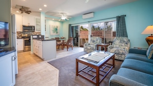 A modern kitchen with a microwave, oven, and dining area. There is a living room with a sofa and chairs. - Hale Hui Kai 304 Two bedroom Two bath with AC and Ocean views (Kihei)