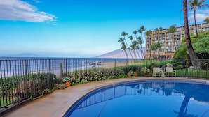 A swimming pool with a view of the ocean and a building in the background. - Hale Hui Kai 304 Two bedroom Two bath with AC and Ocean views (Kihei)