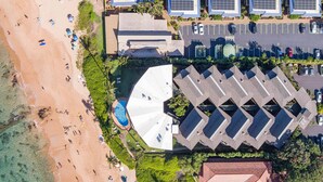 An aerial view of a coastal hotel with a beach, a swimming pool, and a parking area. - Hale Hui Kai 304 Two bedroom Two bath with AC and Ocean views (Kihei)