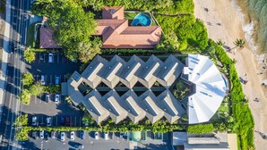 Ein Hotel aus der Vogelperspektive mit Parkplatz, Schwimmbad und Strand.