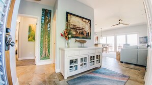 A spacious living room with a large window, a white cabinet with glass doors, and a colorful rug. - Hale Hui Kai 310 Ocean Front Two bedroom / Two bath (Kihei)