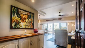 A spacious living area with a large painting, a dining area, and a view of the outdoors. - Hale Hui Kai 308 OCEAN VIEW (Kihei)