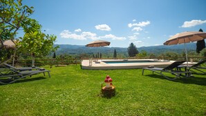 Area piscina con lettini, ombrelloni e una statua decorativa a forma di fungo.