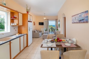 Cozinha moderna com área de jantar, um sofá e vista para o exterior.