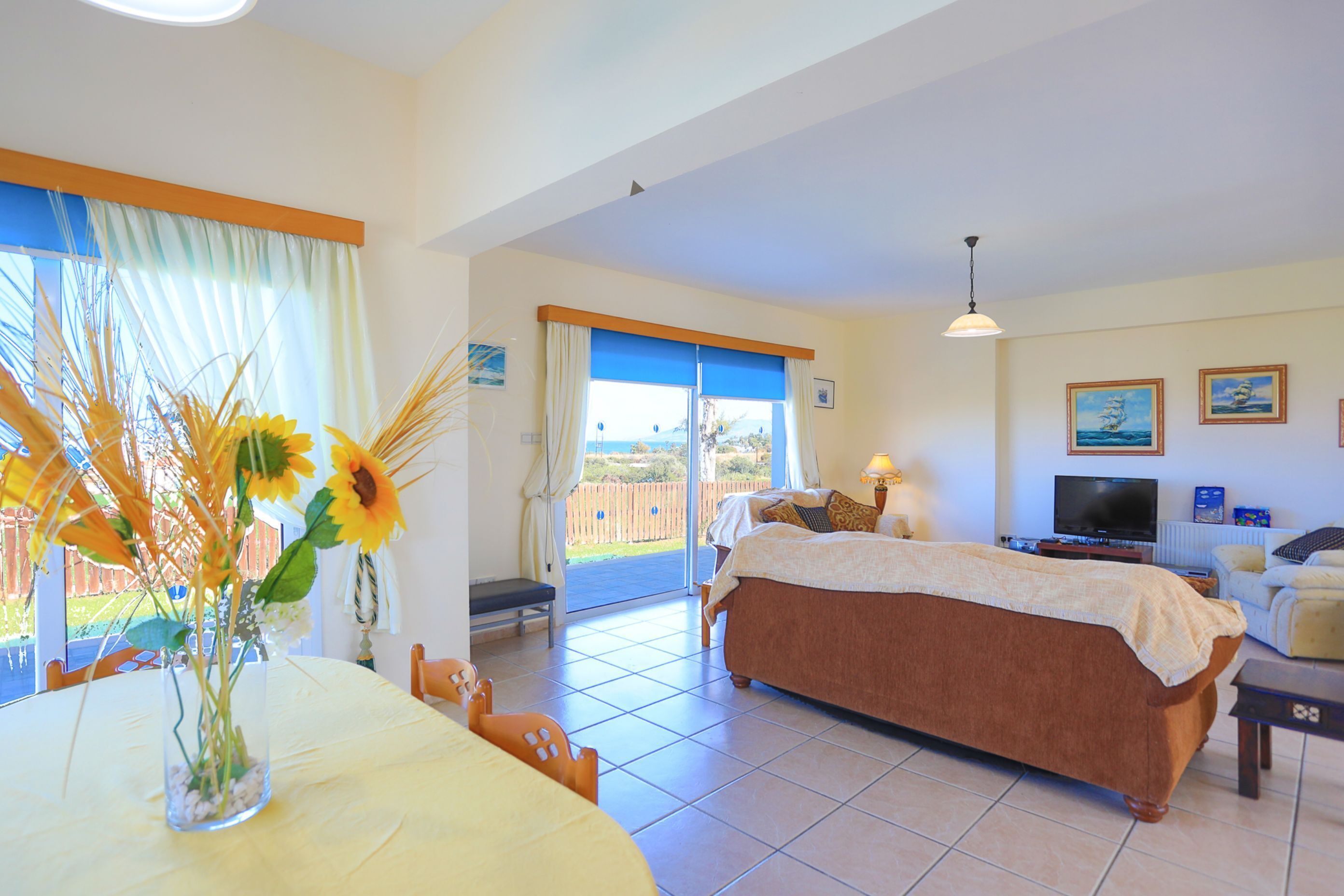 A spacious bedroom with a large bed, a television, and a balcony with a view of the outdoors.