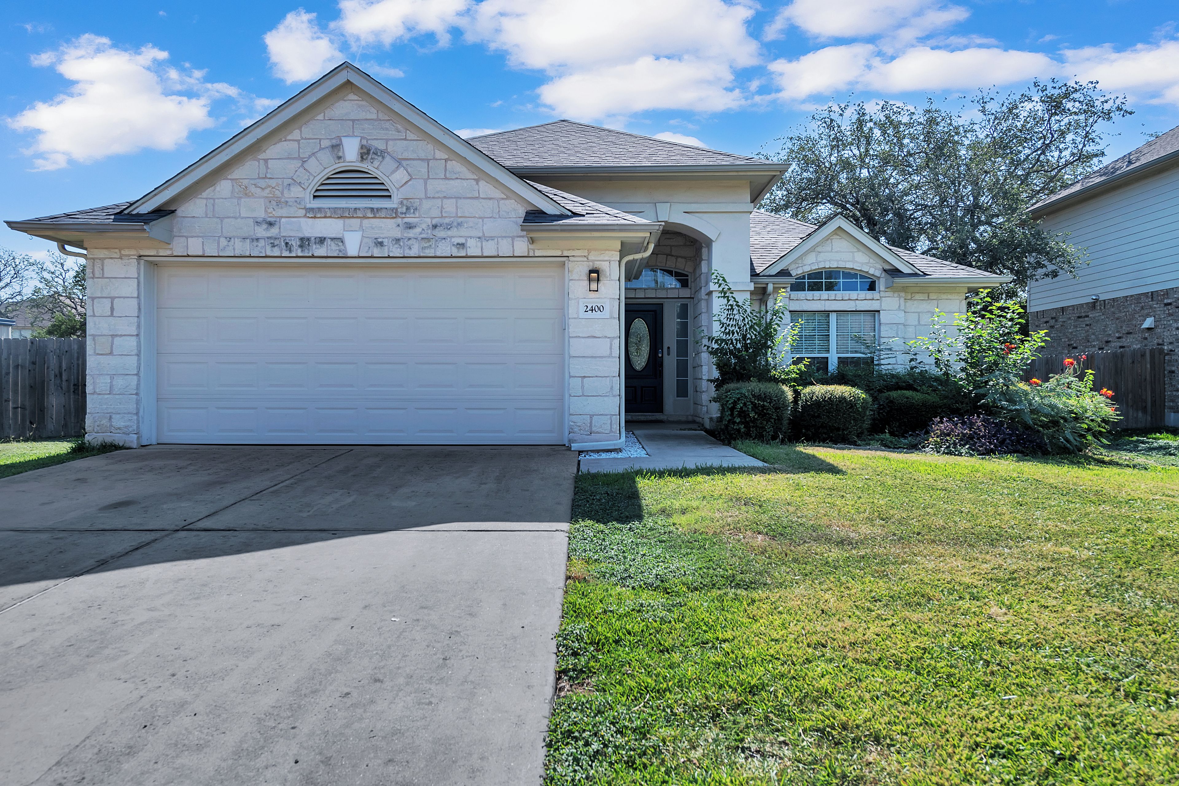 A two-story house with a stone facade, a garage, and a well-maintained lawn.