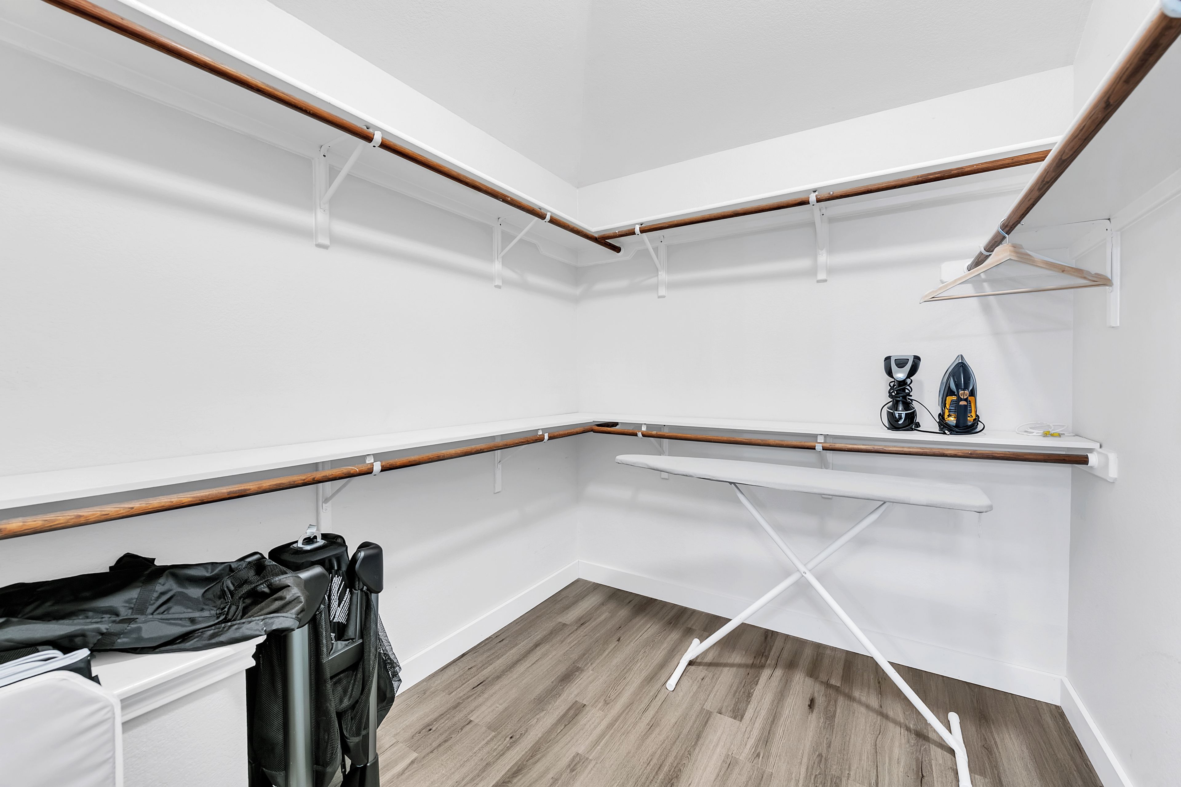 A corner laundry room with wooden beams, white walls, and a wooden floor.