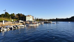 A marina with boats docked, a building with multiple floors, and a clear blue sky. - Studio with balcony and air conditioning (Savudrija)