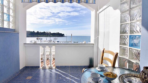 A balcony with a view of the sea, a table with a glass top, and a chair. - Studio with balcony and air conditioning (Savudrija)