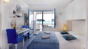A hotel room with a bed, a desk, a chair, a TV, and a view of the sea. - Studio with balcony and air conditioning (Savudrija)