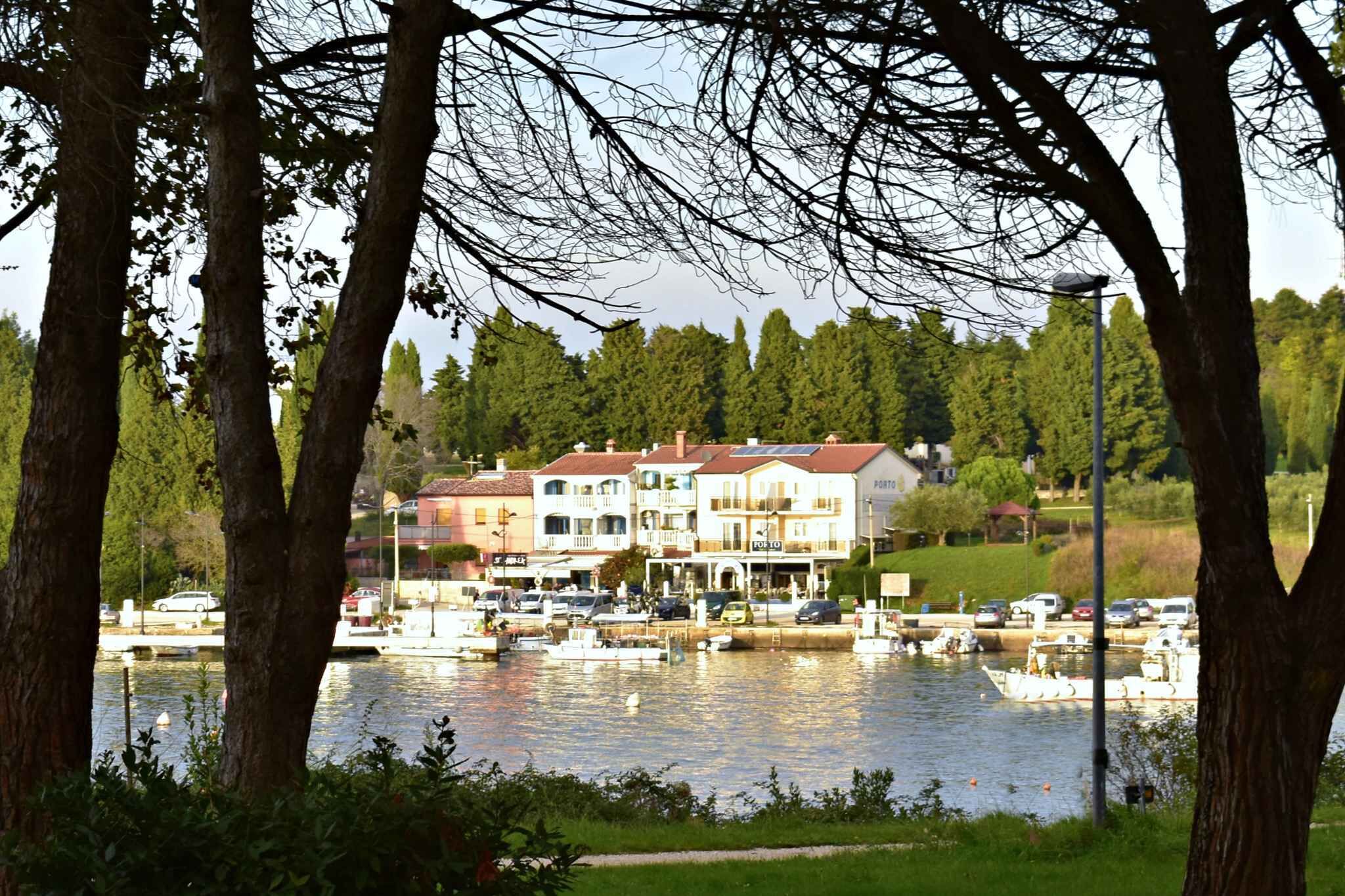Um imóvel à beira-mar com vários edifícios, um cais com barcos e um cenário de árvores e vegetação.