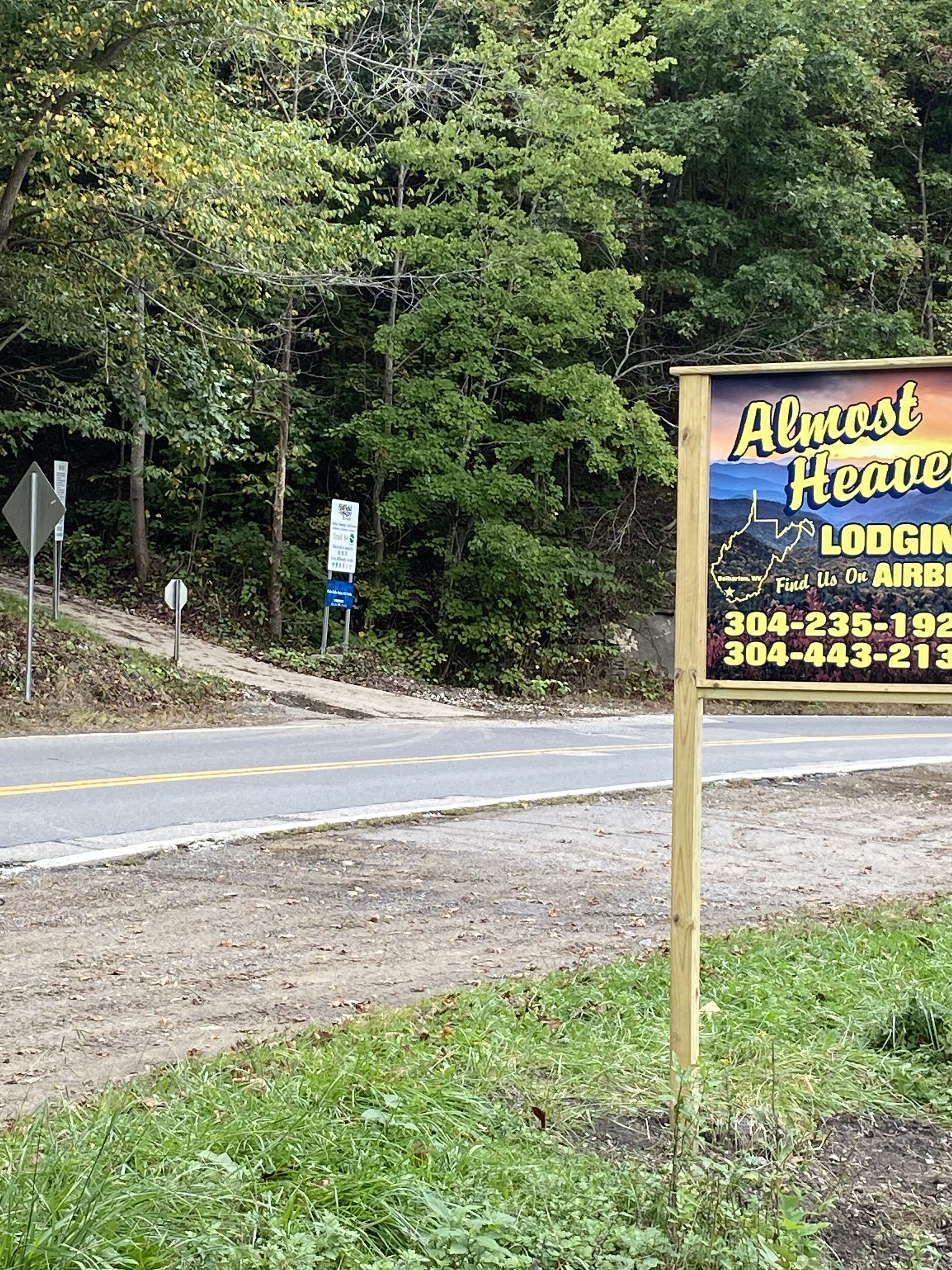 Straßenschild für eine Unterkunft namens 'Almost Heaven' mit Kontaktdaten.