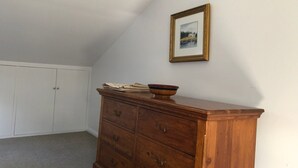A room with a wooden dresser, a framed picture on the wall, and a closet with two doors. - Animal friendly (Terrey Hills)