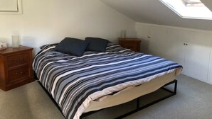 A bedroom with a bed, a nightstand, a dresser, a wardrobe, and a skylight. - Animal friendly (Terrey Hills)