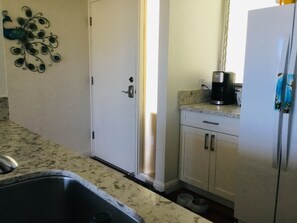 A kitchen with a sink, a coffee maker, and a refrigerator.