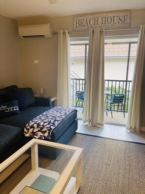 Een slaapkamer met een bed, nachtkastje, salontafel en uitzicht op het balkon.