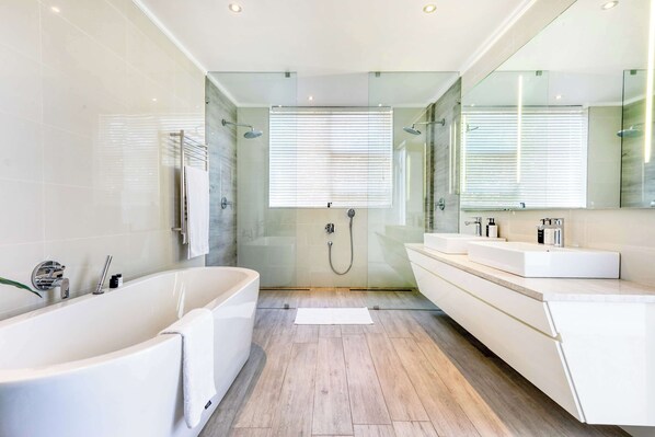 A modern bathroom with a freestanding bathtub, a glass-enclosed shower, and a vanity with a mirror.