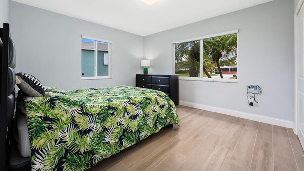 A bedroom with a bed, a dresser, a window with a view, and a ceiling light. - Beach House: Walk 2 Blocks to Beach & Pet Friendly (Hutchinson Island)