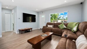 Ein modernes Wohnzimmer mit einem braunen Ledersofa, einem Holztisch und einem flachbildfernseher an der Wand.