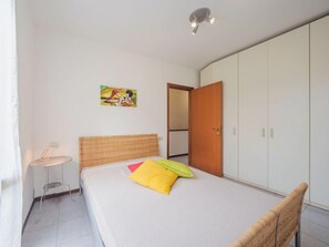 Une chambre à coucher avec un lit, une petite table, une armoire et un tableau accroché au mur.
