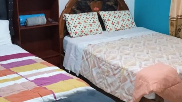Two single beds with different bedding styles, a wooden headboard, and a blue wall. - como es casa, en la ciudad de huarmey a 10 minutos de las playas (Huarmey)