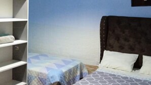 A bedroom with a bed, a nightstand, and a shelving unit against a blue wall. - como es casa, en la ciudad de huarmey a 10 minutos de las playas (Huarmey)