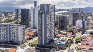 Un edificio de gran altura con varios pisos, rodeado de otros edificios y una calle.