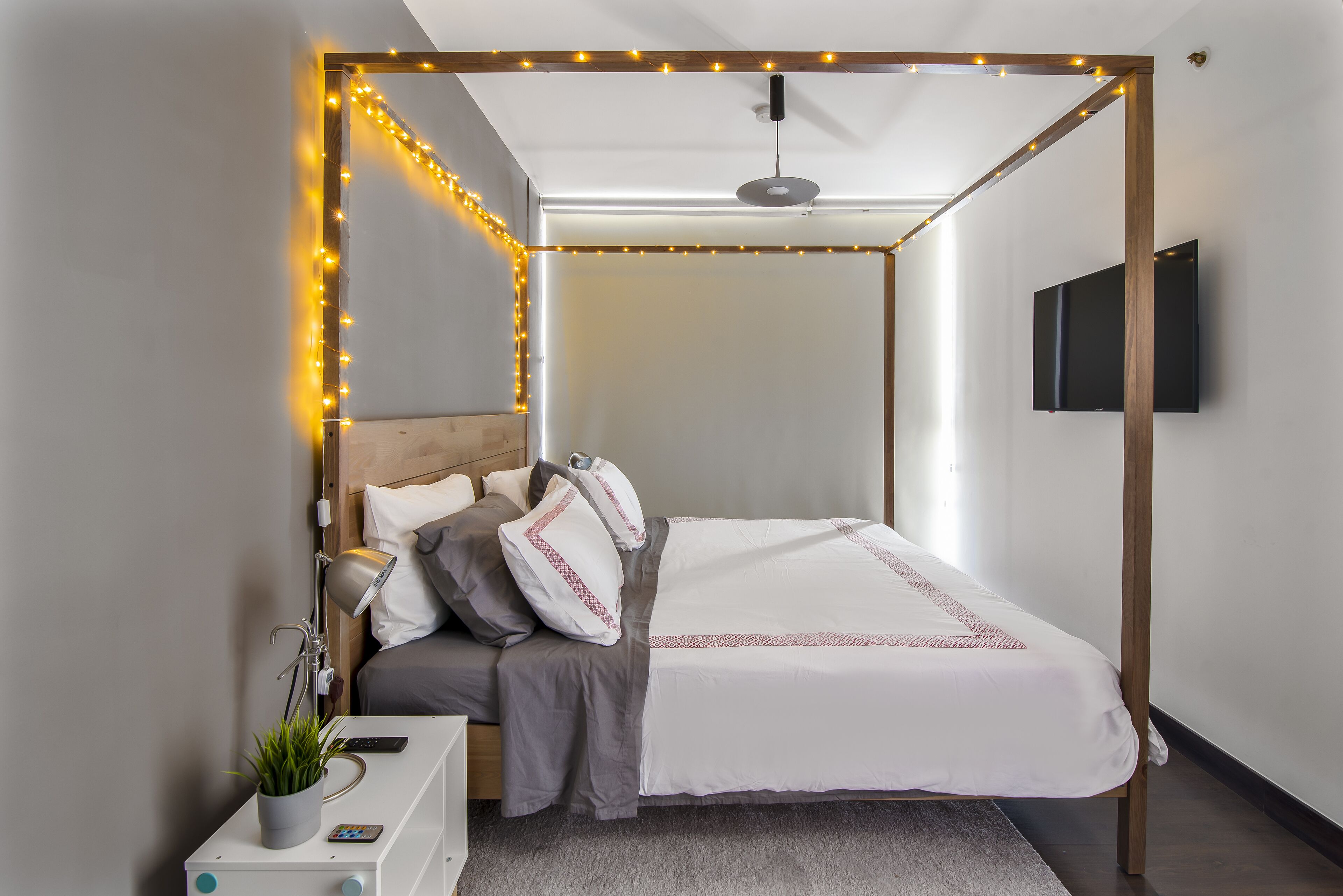 Een moderne slaapkamer met een hemelbed, een flatscreen televisie en sfeerverlichting.