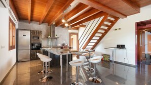 Una cocina moderna con una isla central, electrodomésticos de acero inoxidable y un techo inclinado con vigas a la vista.