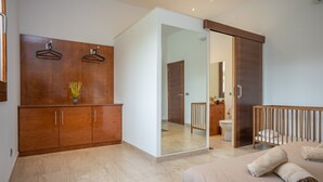 Un dormitorio moderno con una cama grande, un armario de madera y una puerta corredera que da a un baño.