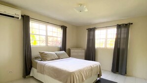 Un dormitorio con cama, cómoda y ventana con cortinas.