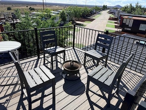 Una terrazza con tavolo e sedie, un braciere e vista su una zona residenziale.