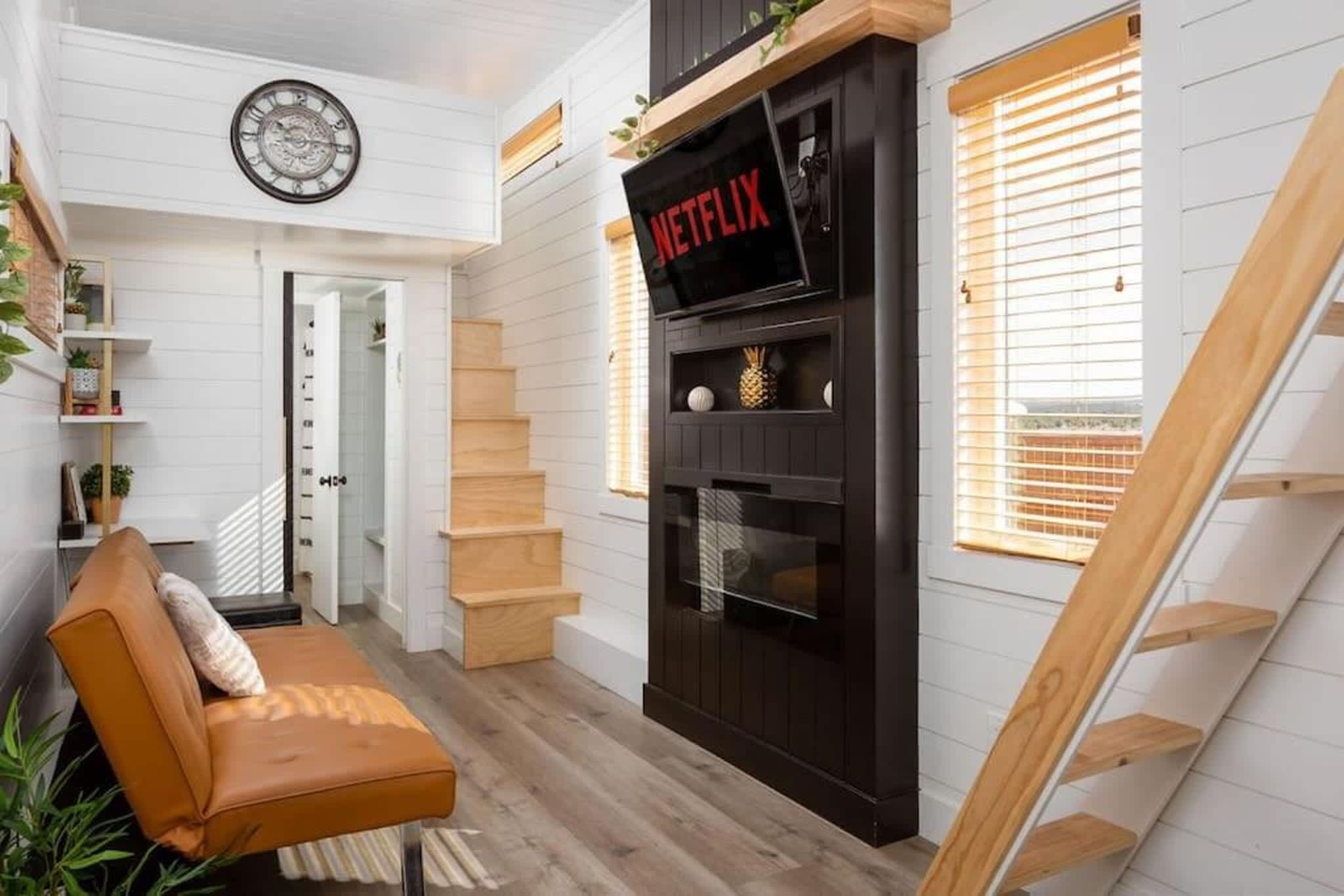A modern interior with a staircase, a sofa, a fireplace, and a clock on the wall.