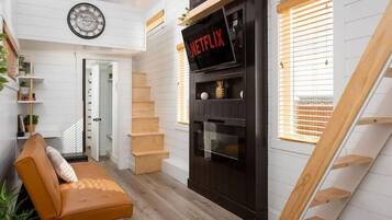 A modern interior with a staircase, a sofa, a fireplace, and a clock on the wall.